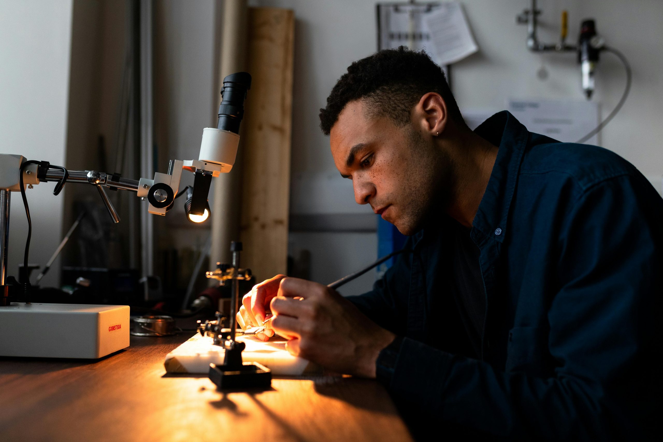 RMDECS engineer performing precision inspection under a stereo microscope
